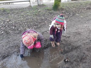 Zwei Kinder stehen im Matsch und spielen