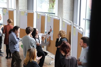 Menschen arbeiten an Stellwänden mit Flip Charts