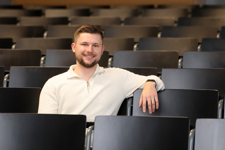 Bild des Absolventen Maximilian Hiller sitzend im Hörsaal