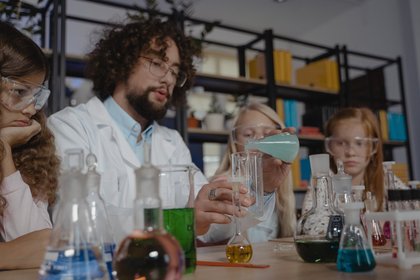 Ein Lehrer macht chemische Experiment zusammen mit Schülern