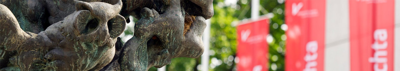 Skulptur vor Haupteingang der Universität Vechta Nahaufnahme von der Skulptur vor dem Universitätshaupteingang. Im Hintergrund Rote Uni Vechta Flaggen.