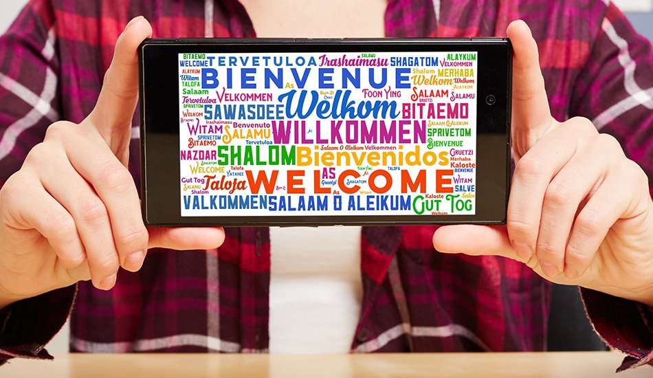 Sprachenzentrum (Robert Kneschke/AdobeStock) Person hält Tablet, dass Willkommen in verschiedenen Sprachen zeigt